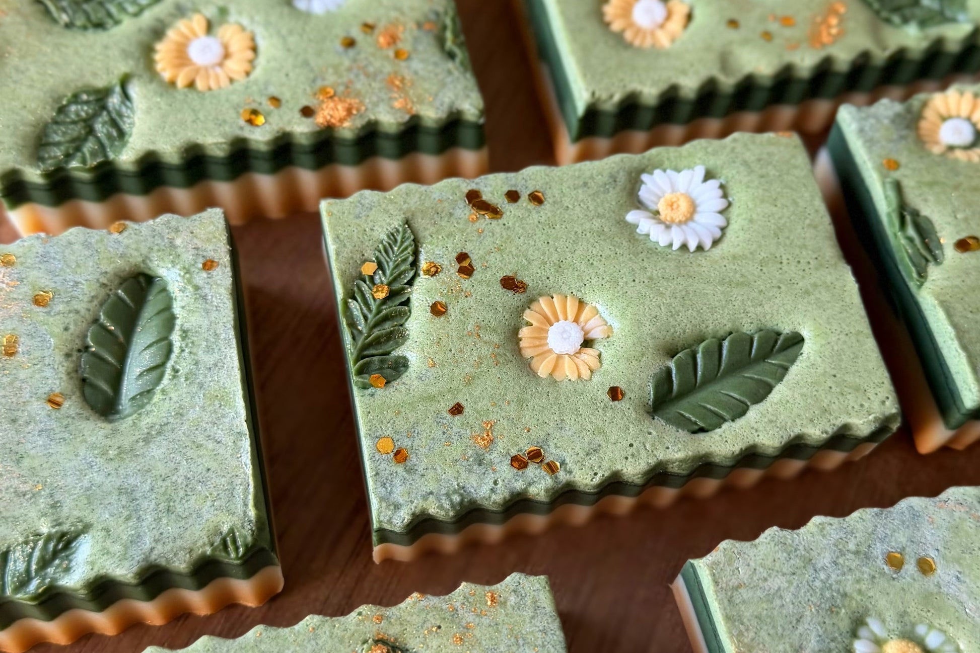 Green soap bars with floral and leaf designs on a wooden surface